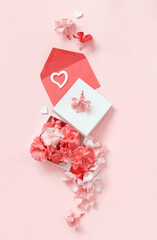 Red envelope, hearts and gift box full of flowers over a light pink background