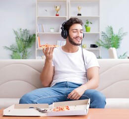 Man eating pizza having a takeaway at home relaxing resting
