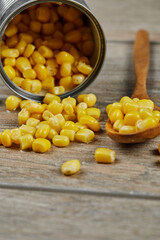 A can of boiled sweet corn on a wooden table with a spoon