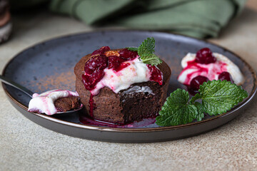 Mini chocolate cake or brownie with cream, cherry and mint on a ceramic plate. Chocolate fondant.