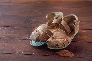 Children's sandals made of leather with a peeled sole. Old worn-out shoes.