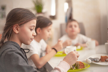 The group of kids eating the easter bread on spring holiday with tea