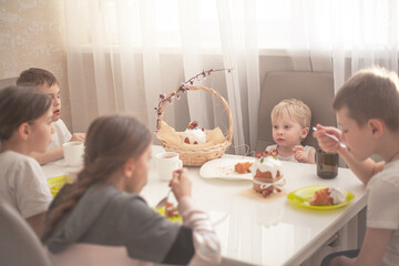 The group of kids eating the easter bread on spring holiday with tea