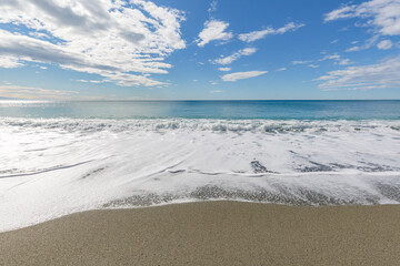 Fototapeta na wymiar Blue sea water waves with white foam and bubbles washes the beach. Winter see. Riva Trigoso on ligurian coast
