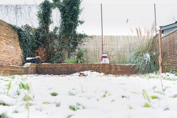 A snowman in a protective mask welcomes the first snow in London in 2021. Winter day during the pandemic coronavirus.