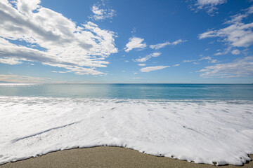 Blue sea water waves with white foam and bubbles washes the beach. Winter see. Riva Trigoso on ligurian coast