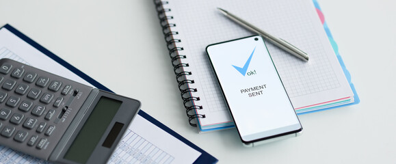 On table lies a smartphone with inscription payment sent documents and calculator