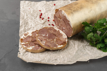 Liver sausage on parchment with parsley on gray background