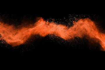 Freeze motion of orange color powder exploding on black background. 