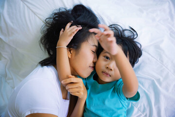 Authentic close up of happy mother and her son in a bed. Concept of new generation, family, parenthood, authenticity, connection.