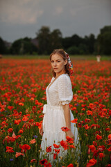 Obraz na płótnie Canvas woman in white dress in a field of poppies