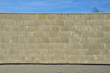 concrete wall made of smooth blocks. high dividing noise wall of the yard. under the wall is a...
