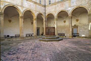 chiostro di un antico castello , con archi in veduta simmetrica con al centro un pozzo con decorazione in ferro