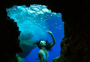 A young woman free diving apnea underwater cave.  