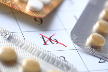 birth control pills and calendar with red mark on table 