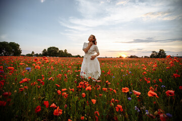 girl in a white dress in a field of red poppies