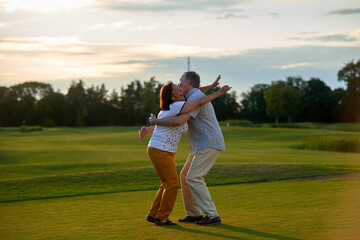 Loving mature couple hugging outdoors. Man and woman on the green field.
