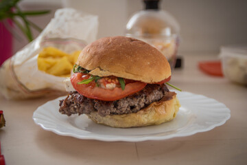 Side low profile photo of a delicious hamburger with brie cheese recieved as a take away or delivery during lockdown.