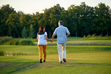 Obraz premium Walking couple on the field. Mature man and his wife on the green lawn.