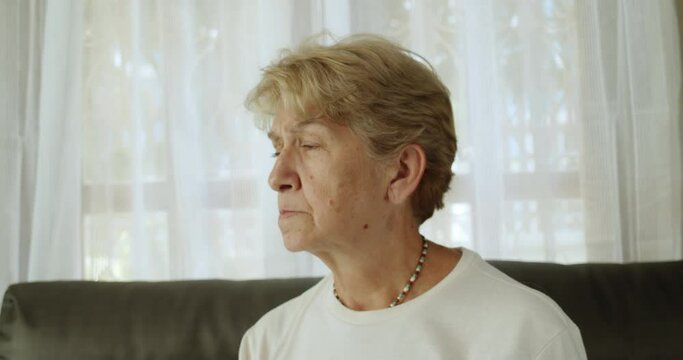 An elderly woman after retirement cut short hair with white and bronze hair wearing long sleeve T-shirt and a necklace has vision problems.