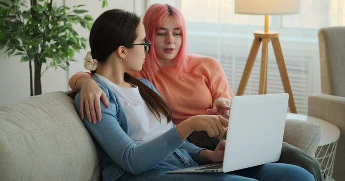 Lesbian couple discussing over laptop on sofa at home