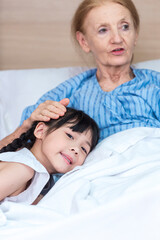Asian Lovely girl visit and encourage grandmother on patient bed in hospital