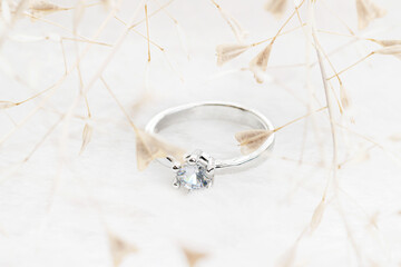 Wedding silver traditional with brilliant ring and flowers around on white fur background macro