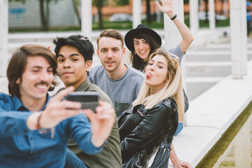 Group of multiethnic friends outdoor having fun and taking selfie