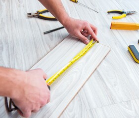 Fototapeta na wymiar Repairman laying laminate flooring at home
