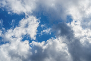 Bright blue sky shows through gaps in white-gray clouds. Meteorology, clouds and wind.  Changing weather from sunny to overcast. Weather forecast.