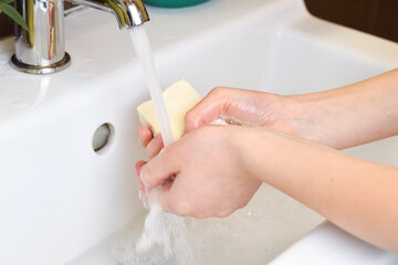 Young girl washing hands with soap over sink under the faucet. Hand disinfection during a coronavirus pandemic. Hygiene concept.