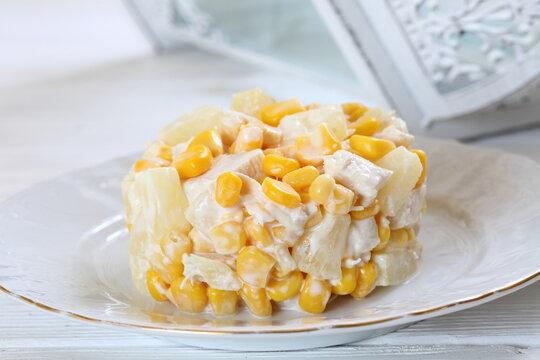 Salad with chicken, pineapple and corn with champagne on a white plate