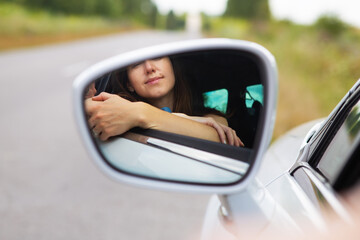 A young girl driving a car, the girl looks in the side mirror. Delivery for the right to drive a car.