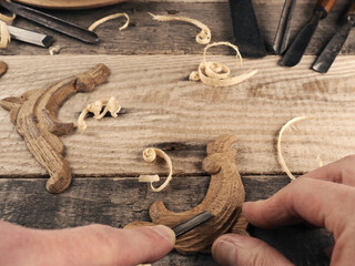 Carved oak decorative elements on a rustic workbench with chisels, wood working concept