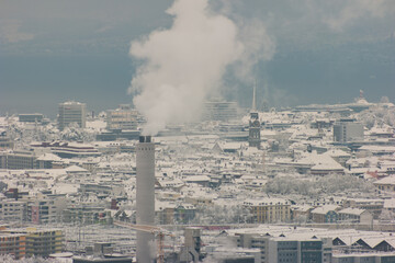 Aerial view of smoking chimney in snow covered Zurich city Switzerland after record high snowfall cloudy day