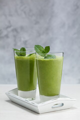 Freshly blended green fruit smoothie in glass.
