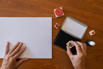 Woman's hands moistening a heart stamp ready for stamping. Top view.