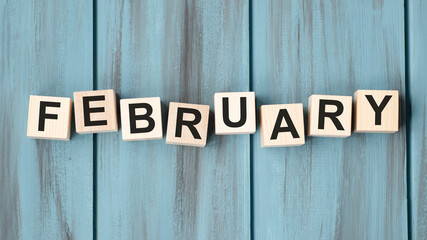 February text on wooden cubes on wooden background.