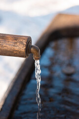 Clean running drinking water from a forest fountain tap in the winter in Switzerland