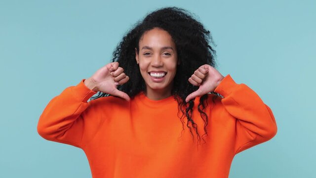 Confident smiling cheery young african woman with curly hair 20s years old wearing basic casual orange sweatshirt pointing fingers on herself isolated on pastel blue color background studio portrait