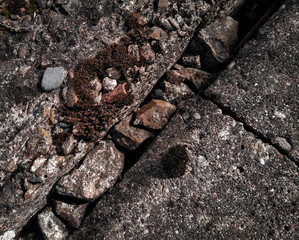 Surface of concrete and crushed stone texture with gap, moss and small pebbles. 