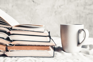 Stack of opened books with a cup of coffee in bed