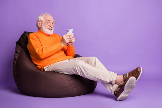 Full Body Profile Photo Of Handsome Cheerful Person Sit Soft Chair Wear Trousers Footwear Isolated On Violet Color Background