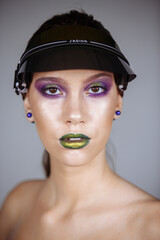 portrait of a girl with bright makeup and green lips in a summer cap