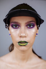 portrait of a girl with bright makeup and green lips in a summer cap