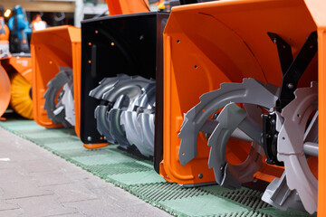 Showcase in a hypermarket with gasoline snow blowers, bucket and auger close-up. Selective focus.