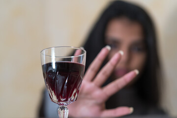 Giving up alcohol. A young woman at the table refuses a glass of red wine with her hand