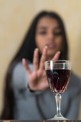 Giving up alcohol. A young woman at the table refuses a glass of red wine with her hand