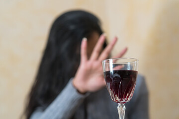 Giving up alcohol. A young woman at the table refuses a glass of red wine with her hand