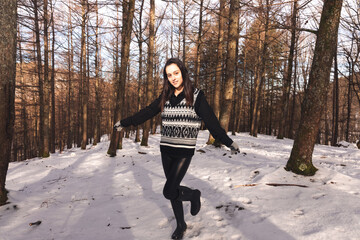 Young caucasian woman playing on a snowy forest.